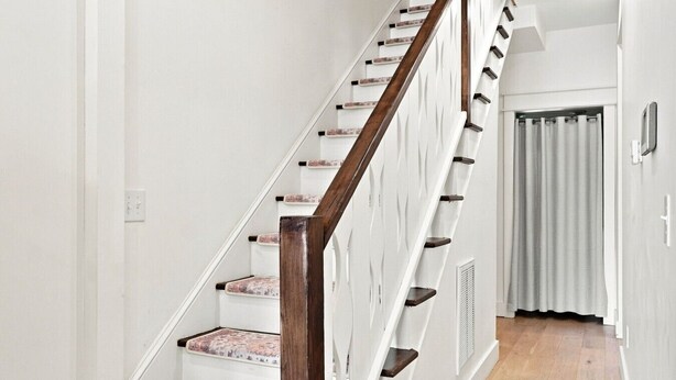 A staircase with wooden handrails and white walls.