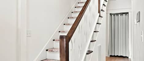 A staircase with wooden handrails and white walls.