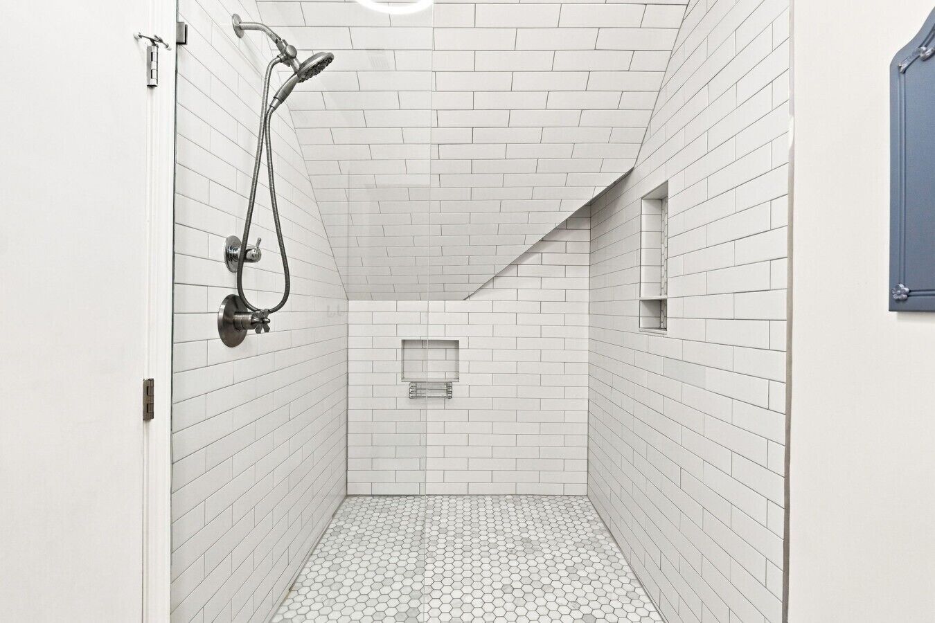 A narrow, tiled shower area with a showerhead and a towel rack.