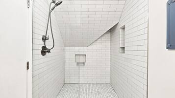 A narrow, tiled shower area with a showerhead and a towel rack.