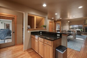 A modern kitchen with wooden cabinets, a granite countertop, and a built-in island. - Big Sky Escape - Private Patio & Grill (Big Sky)