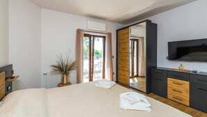 A modern bedroom with a large bed, a TV, a mirror, and a view of the outdoors. - Stunning home in Sajini (Sajini)