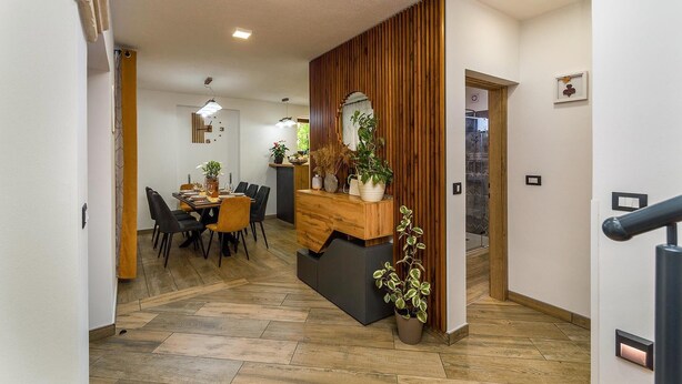 A modern interior with a wooden reception desk, a dining area with a large table and chairs, and a staircase leading to another level. - Stunning home in Sajini (Sajini)