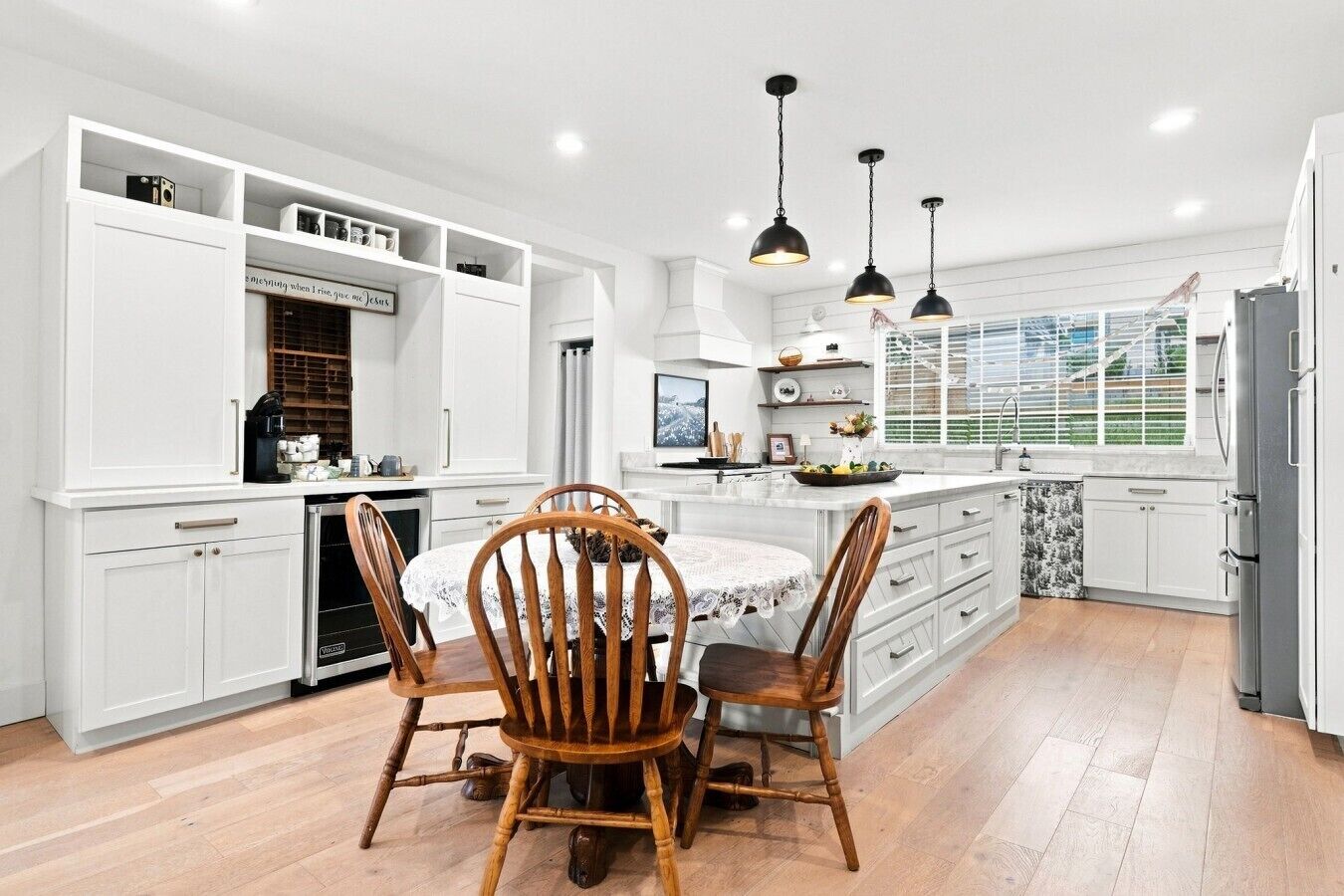 Une cuisine moderne avec des meubles blancs, un îlot central et des luminaires suspendus.