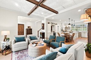 A spacious living room with a fireplace, a dining area with wooden chairs, and a kitchen with white cabinets. - The Ball Ground House (Ball Ground)