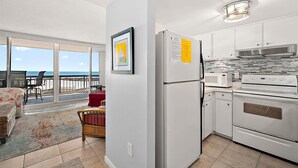 Una cocina moderna con refrigerador, microondas y horno. Hay un balcón con vista a la playa.