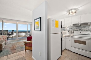 Eine moderne Küche mit Kühlschrank, Mikrowelle und Backofen. Ein Balkon bietet Blick auf den Strand.