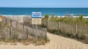 Una playa con una cerca de madera y un cartel.