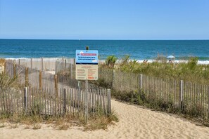 Ein Strand mit Holzlattenzaun und einem Schild.