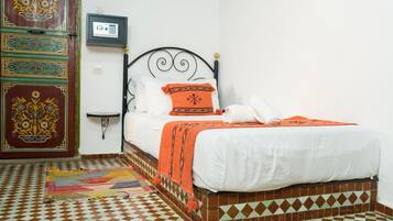 A room with a bed, a patterned rug, a decorative door, and a wall-mounted radio.