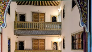 Une cour traditionnelle agrémentée de balcons décoratifs et de carreaux aux motifs variés.