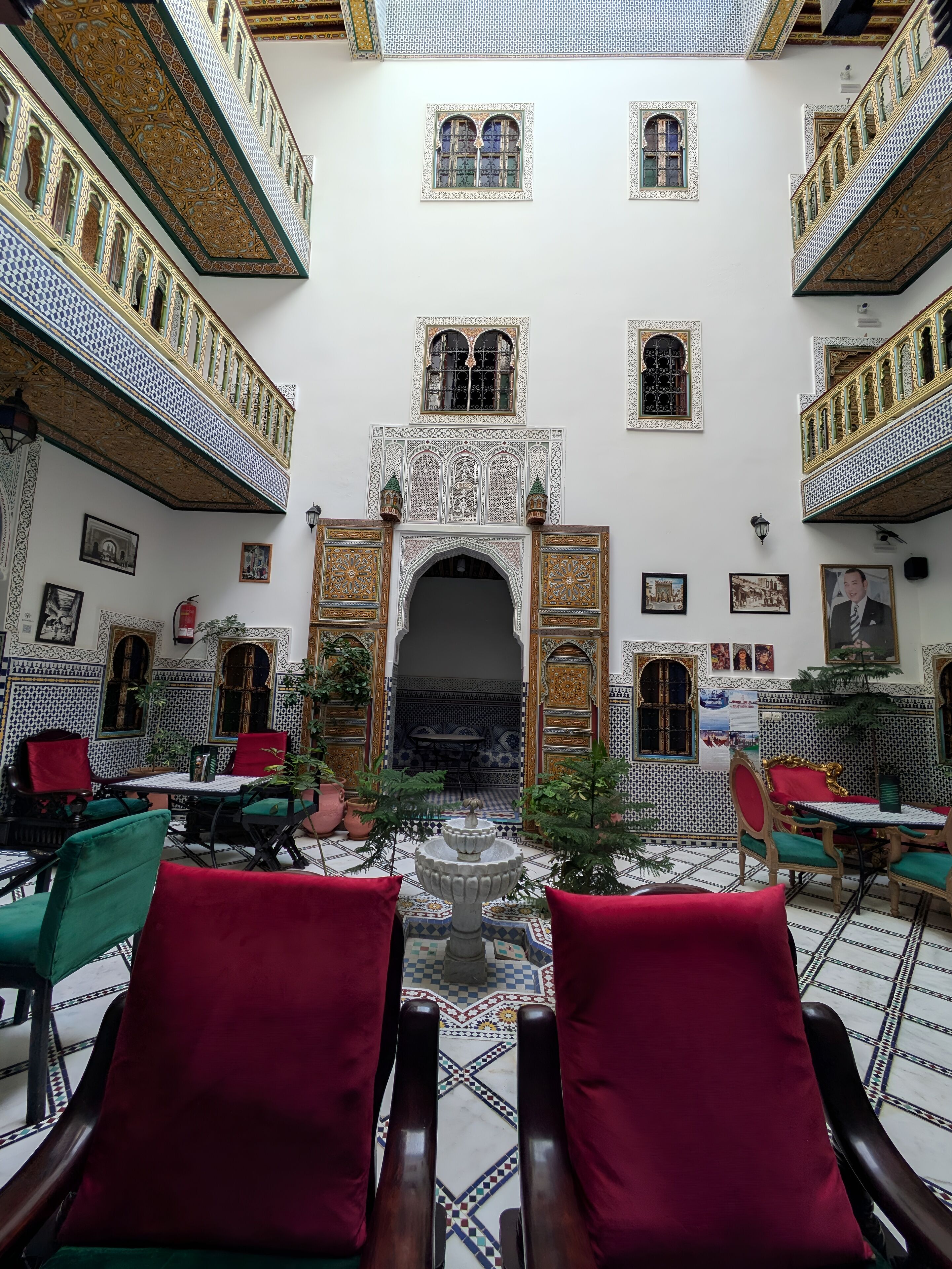 A courtyard with ornate arches, tiled flooring, and seating areas.