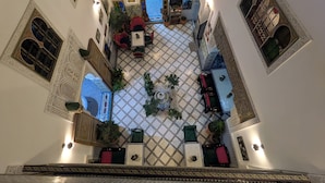 Une cour intérieure agrémentée de motifs complexes en mosaïque, d’une fontaine centrale et d’espaces aménagés pour s’asseoir.