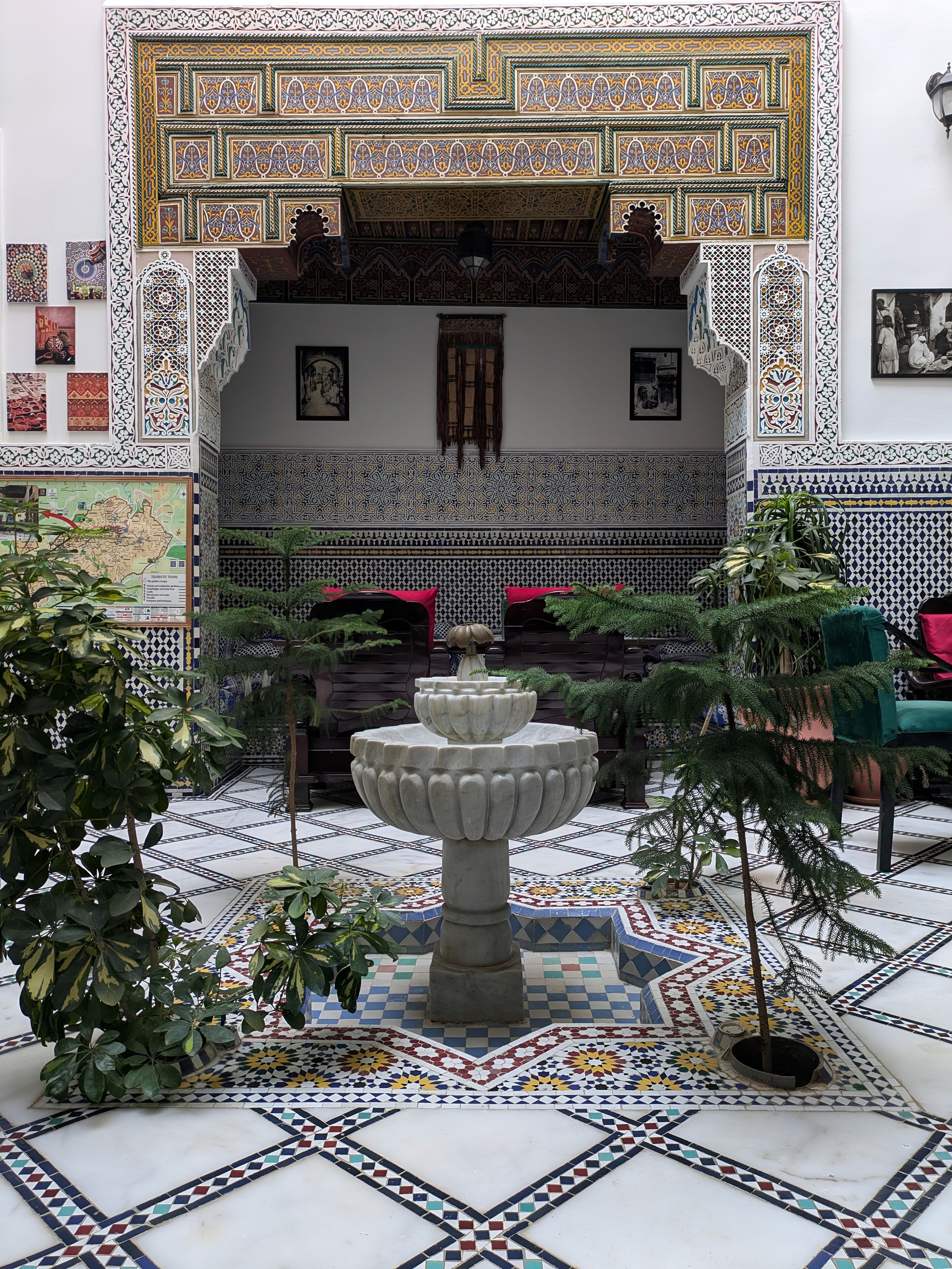 Un patio con una fuente central, suelo de baldosas y paredes decorativas.