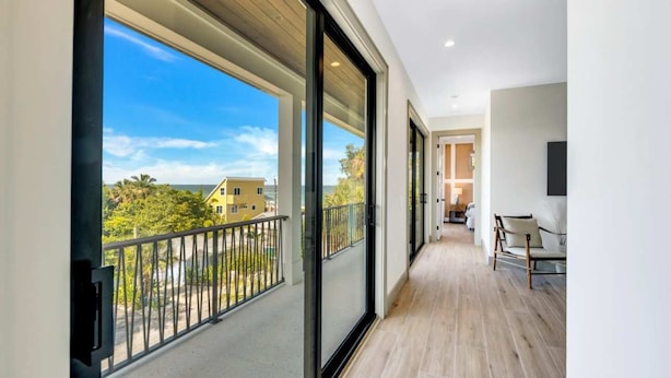Un balcon avec vue sur la mer et sur d’autres bâtiments, un plancher en bois et une chaise.