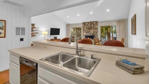 A modern kitchen with a double sink, a dishwasher, and a stone accent wall. - King's Beach condo with stunning views! (Kings Beach)