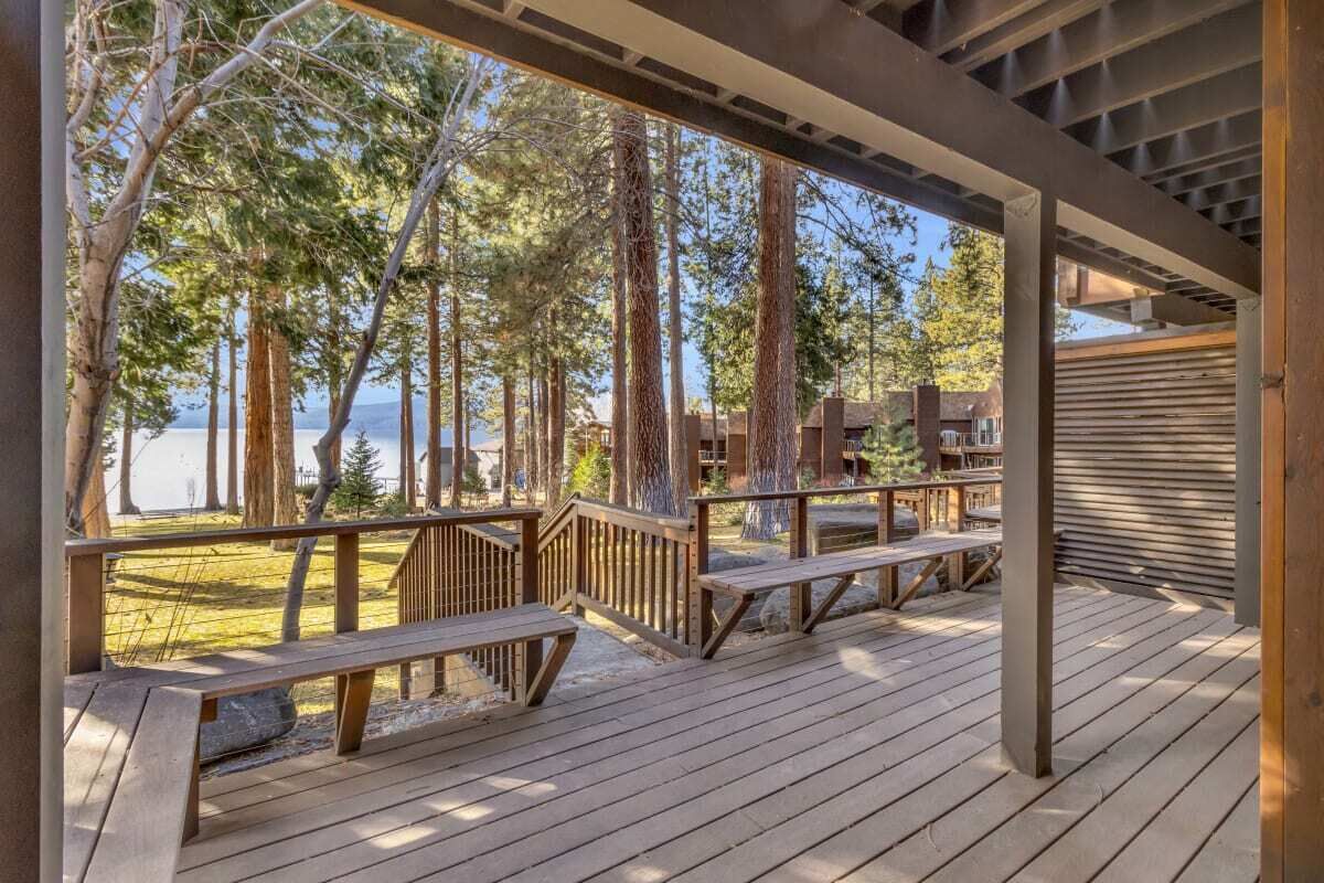Une terrasse en bois, dotée de bancs, qui offre une vue sur une zone boisée et un plan d’eau.