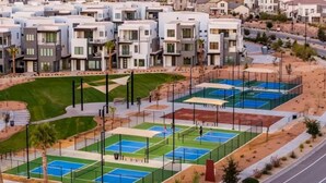 Un quartier résidentiel avec des maisons modernes, un court de tennis et un parc aménagé.