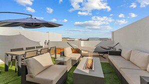 Une terrasse sur le toit, aménagée avec du mobilier d’extérieur, un foyer et un hamac.