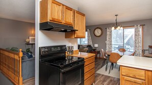 Una cucina con mobili in legno, un fornello nero e un'area pranzo con tavolo e sedie.