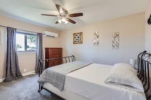 A bedroom with a bed, a ceiling fan, an air conditioning unit, a dresser, and decorative wall art. - The Country Farmhouse (Platteville)