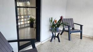 A clean, modern outdoor seating area with two lounge chairs and a small table, surrounded by potted plants. - Hotel Feliz Estancia (La Romana)