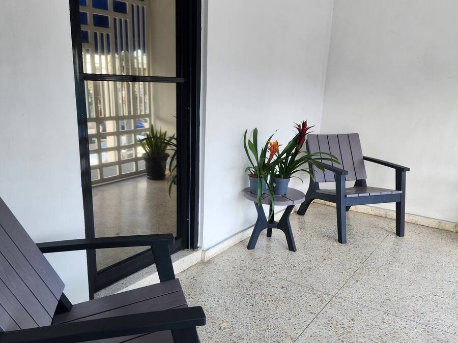 A clean, modern outdoor seating area with two lounge chairs and a small table, surrounded by potted plants.