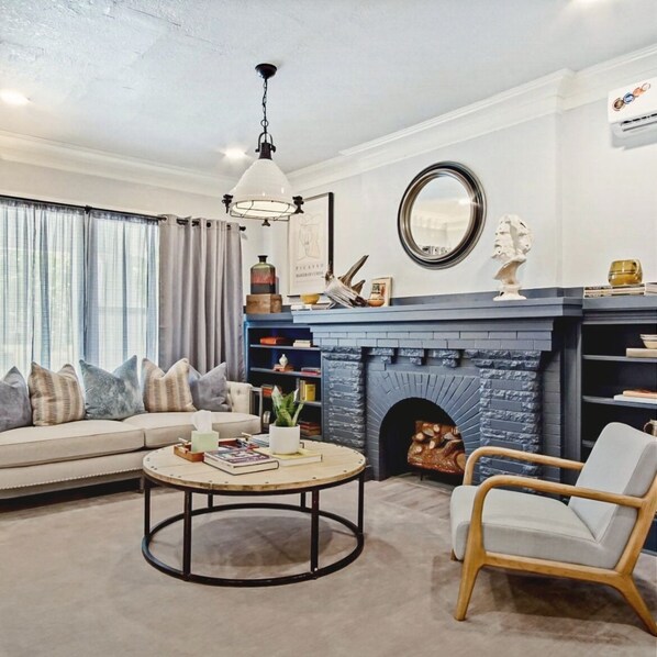 A living room with a sofa, a round coffee table, a fireplace, and a bookshelf. - 1BR near St. Anthony, OU Health & the VA — set up for work and medical stays (Oklahoma City)