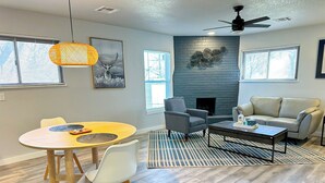 Una sala de estar moderna con chimenea, un comedor con una mesa redonda y un sofá.