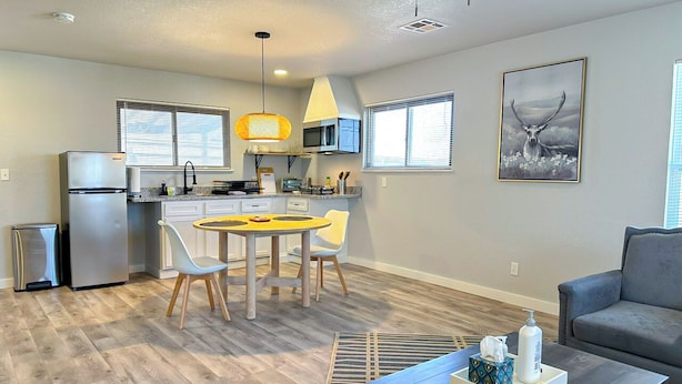 Una cocina moderna con una mesa de comedor y sillas, un sofá gris y una mesa de centro con objetos encima.