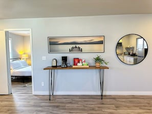 Un salon moderne avec une table basse en bois, un tableau encadré au-dessus et un miroir rond accroché au mur.