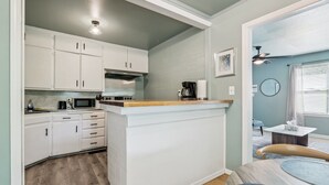 A compact kitchen with white cabinets, a microwave, and a coffee maker. - 2BR with laundry near Rose State & Tinker — booked for the washer/dryer (Midwest City)