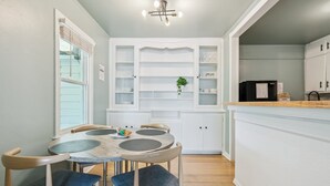 A kitchen with white cabinets, a dining table with chairs, and a refrigerator. - 2BR with laundry near Rose State & Tinker — booked for the washer/dryer (Midwest City)
