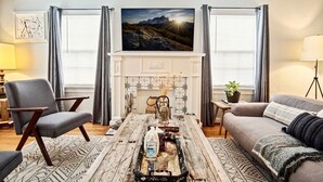 Un salon avec une cheminée, un canapé, un fauteuil et une table basse agrémentée d’objets décoratifs.