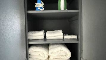 Ein Metallschrank mit Einlegeböden, der gefaltete Handtücher und ein blau-weißes Objekt enthält.