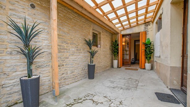 A covered outdoor area with stone walls, wooden beams, and potted plants. - La Lukas - MUSSY SUR SEINE (MUSSY SUR SEINE)