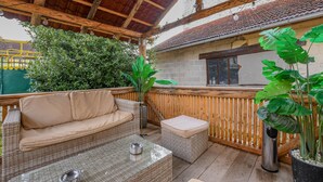 An outdoor patio area with a wicker sofa, a small table, and potted plants. - La Lukas - MUSSY SUR SEINE (MUSSY SUR SEINE)