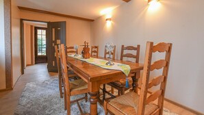 A dining room with a wooden table, chairs, and a chandelier. There is a window with a view of trees and a door leading to another room. - La Lukas - MUSSY SUR SEINE (MUSSY SUR SEINE)