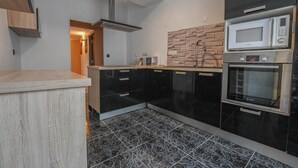 A modern kitchen with black cabinets, a stainless steel range hood, a microwave, and an oven. - La Lukas - MUSSY SUR SEINE (MUSSY SUR SEINE)