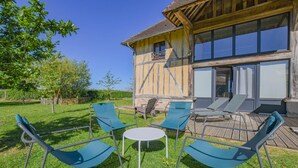 Ett trähus med en veranda, utomhusmöbler och en klar himmel.