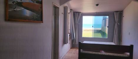 Un pasillo con un banco, un cuadro y vista a la playa a través de una ventana.