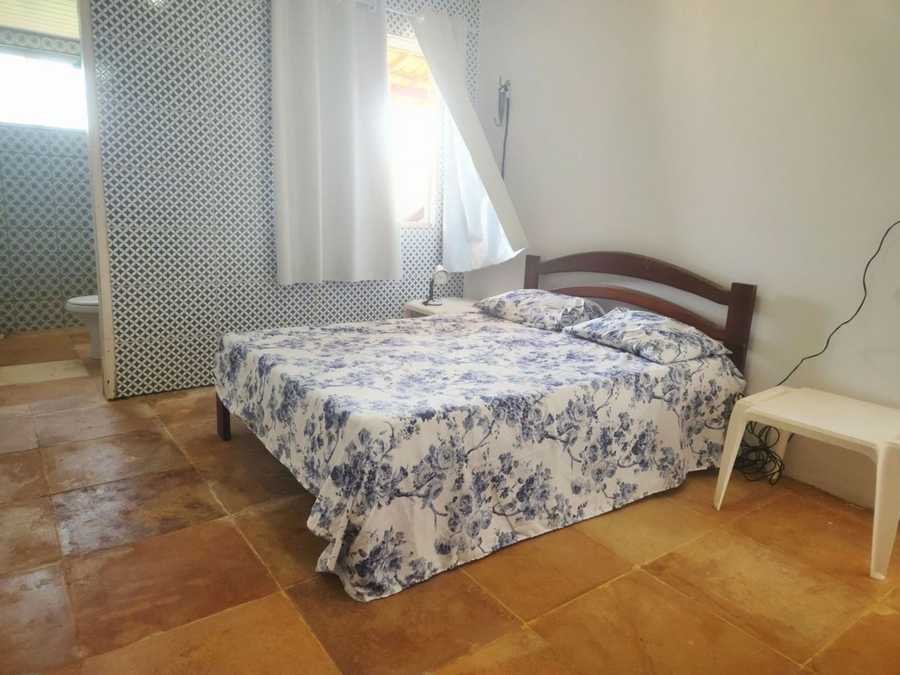 A bedroom with a bed, a bedside table, a mirror, and a shower.
