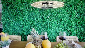 A table set with fruits, glasses of juice and wine, and a sign that reads "Call me The Breeze".