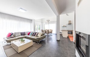 Un salon moderne avec un canapé d’angle, une table basse en verre et une cheminée.