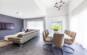 Un salon moderne comprenant un canapé, un téléviseur, une table à manger et des chaises.