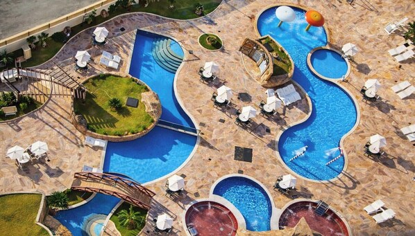 An aerial view of a resort with multiple swimming pools, sun loungers, and a small waterfall feature. - Caldas Novas - Golden Dolphin Supreme (Caldas Novas)