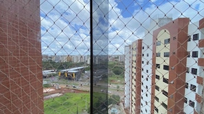 A view through a chain-link fence of a cityscape with high-rise buildings, a road, and a green area. - Caldas Novas - Golden Dolphin Supreme (Caldas Novas)