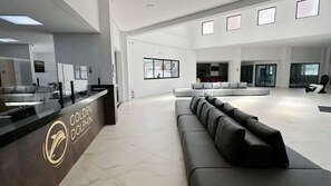 A spacious lobby with a reception desk labeled "Golden Dolphin," a large gray sofa, and a modern interior design. - Caldas Novas - Golden Dolphin Supreme (Caldas Novas)