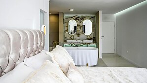 Ein Schlafzimmer mit einem großen Bett, einem Schminktisch mit Spiegel und einer Tür zu einem weiteren Raum.