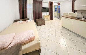 A hotel room with a bed, a small sofa, a kitchenette, and a bathroom. - Stunning apartment in Okrug Gornji with outdoor swimming pool (Okrug Gornji)